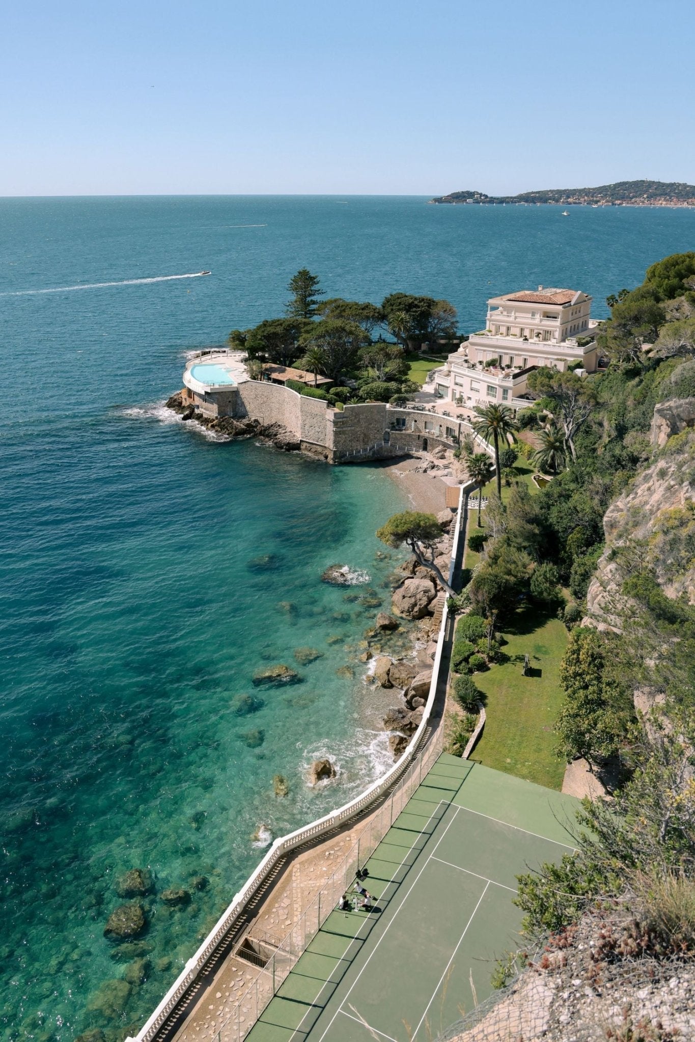 Stunning view of Hôtel Cap-Estel, featuring Cap Estel Print with turquoise waters and tennis court on the Côte d’Azur.