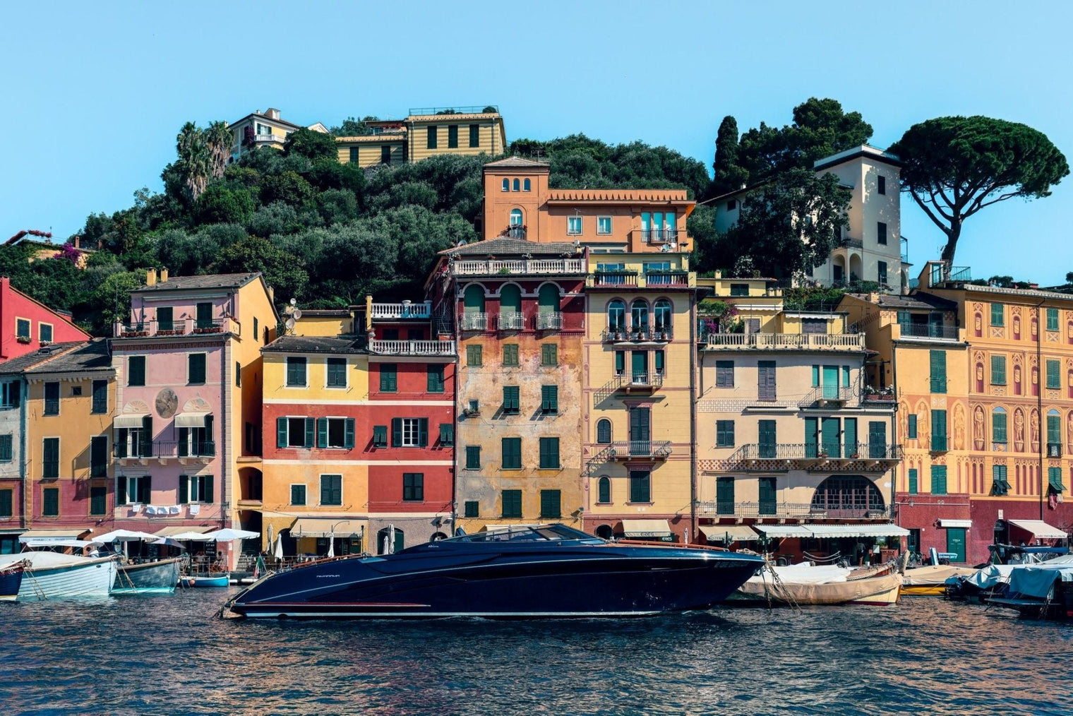 Riva Print of a sleek yacht moored in Portofino harbor with colorful buildings in the background.
