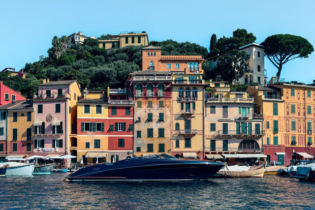 Riva Print of a sleek yacht moored in Portofino harbor with colorful buildings in the background.