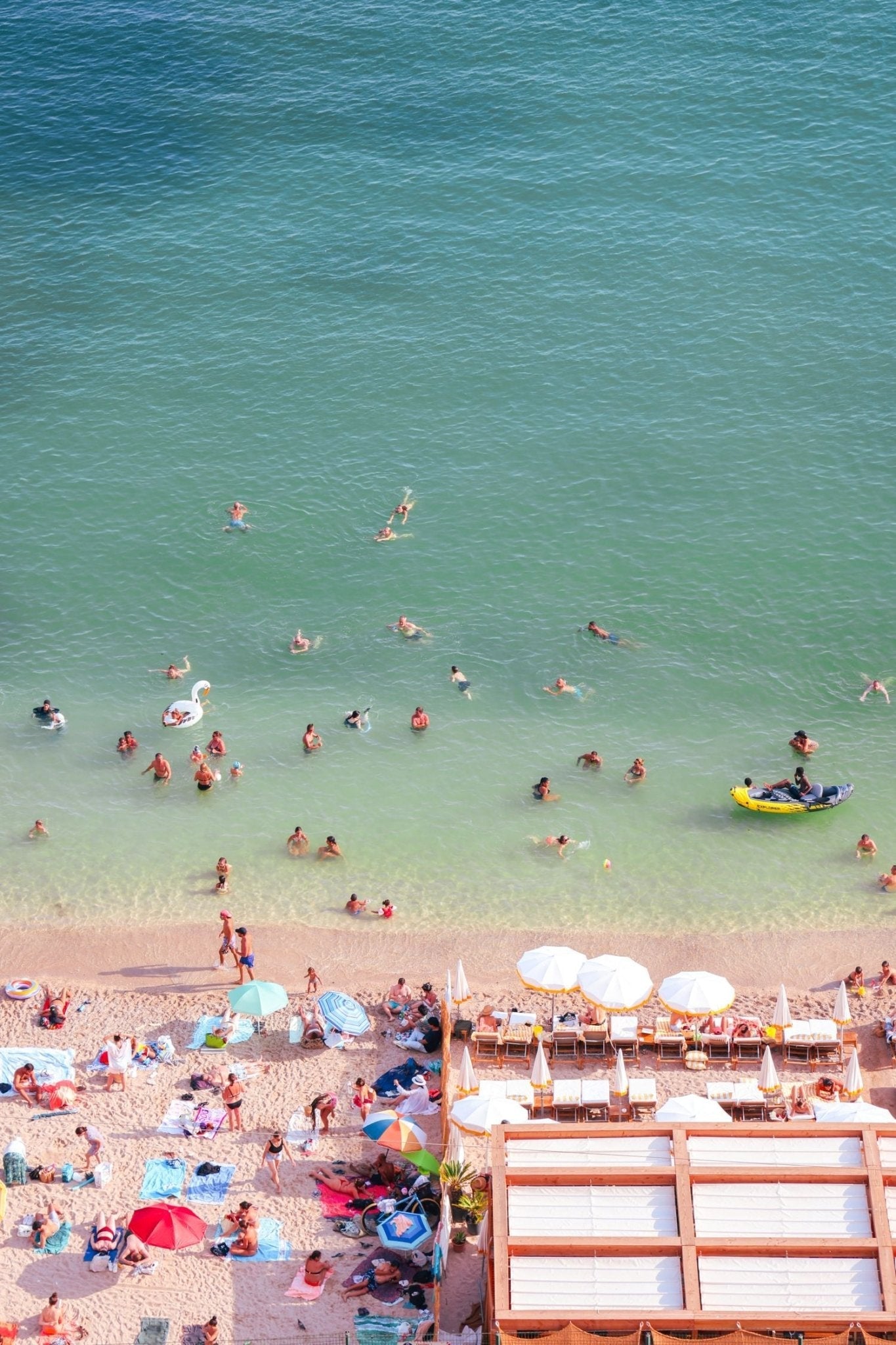 Villefranche Print capturing vibrant beach scene with sunbathers and swimmers in turquoise waters of Côte d’Azur.