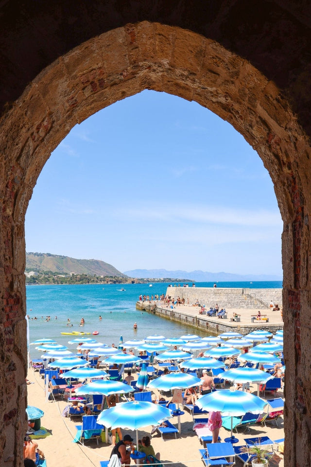 View of La Spiaggia del Porto Vecchio from Porta Pescara, featuring a Céfalu Print of beach umbrellas and stunning sea.