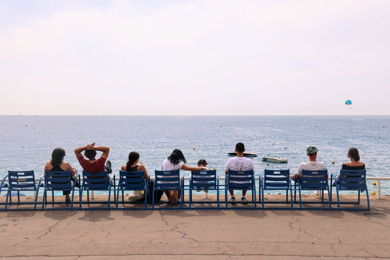 People relaxing on chairs overlooking the sea, capturing the essence of Nice Print along the Promenade des Anglais.